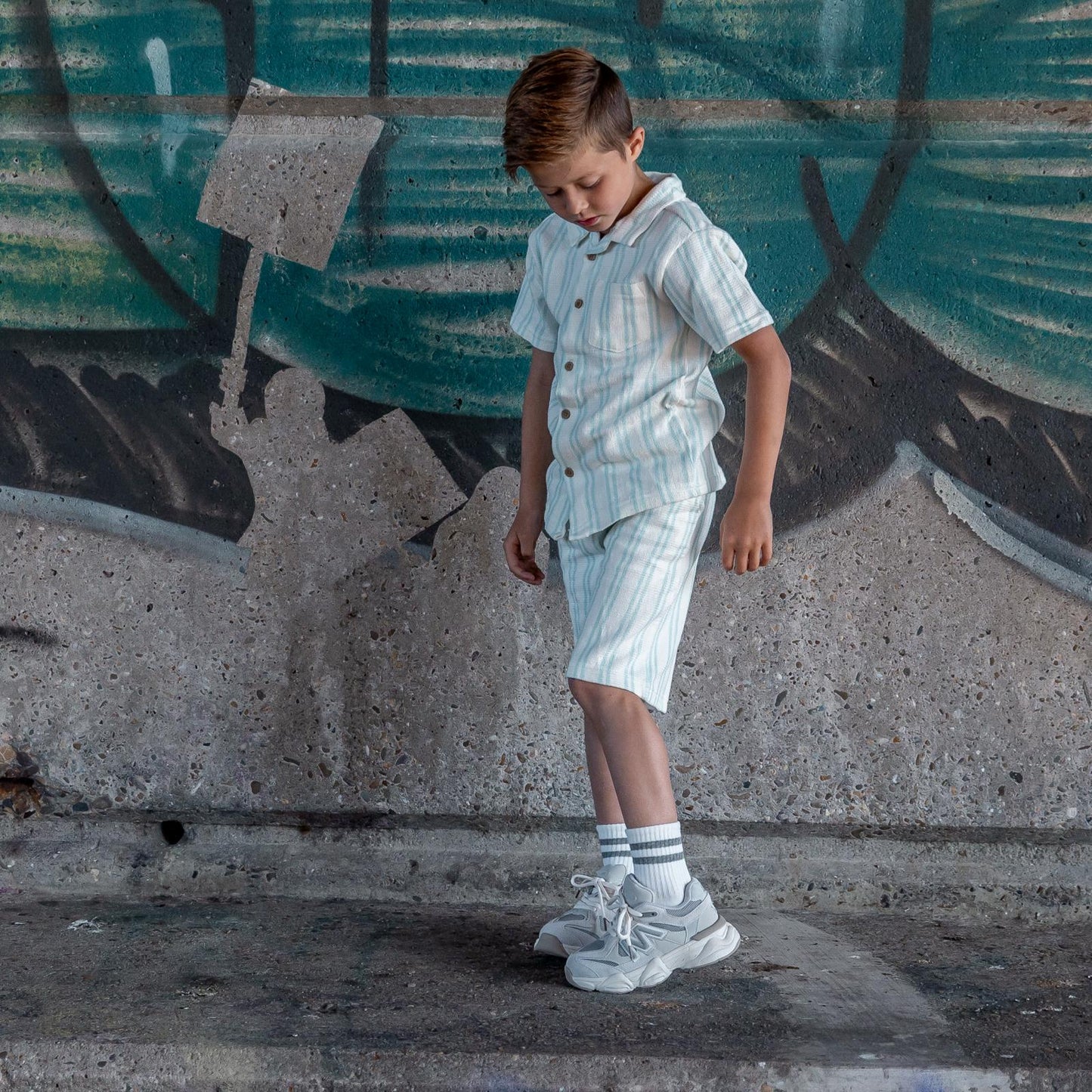 Jongen met Styloz Ivory kindersneakers van Lilpataz die zijn opgetilde voet bekijkt – trendy en comfortabele kindersneakers